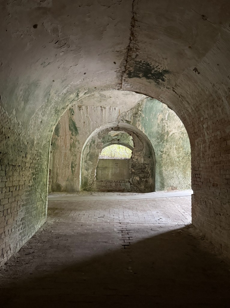 Fort tunnels lines with green moss and sun shining through the right side.