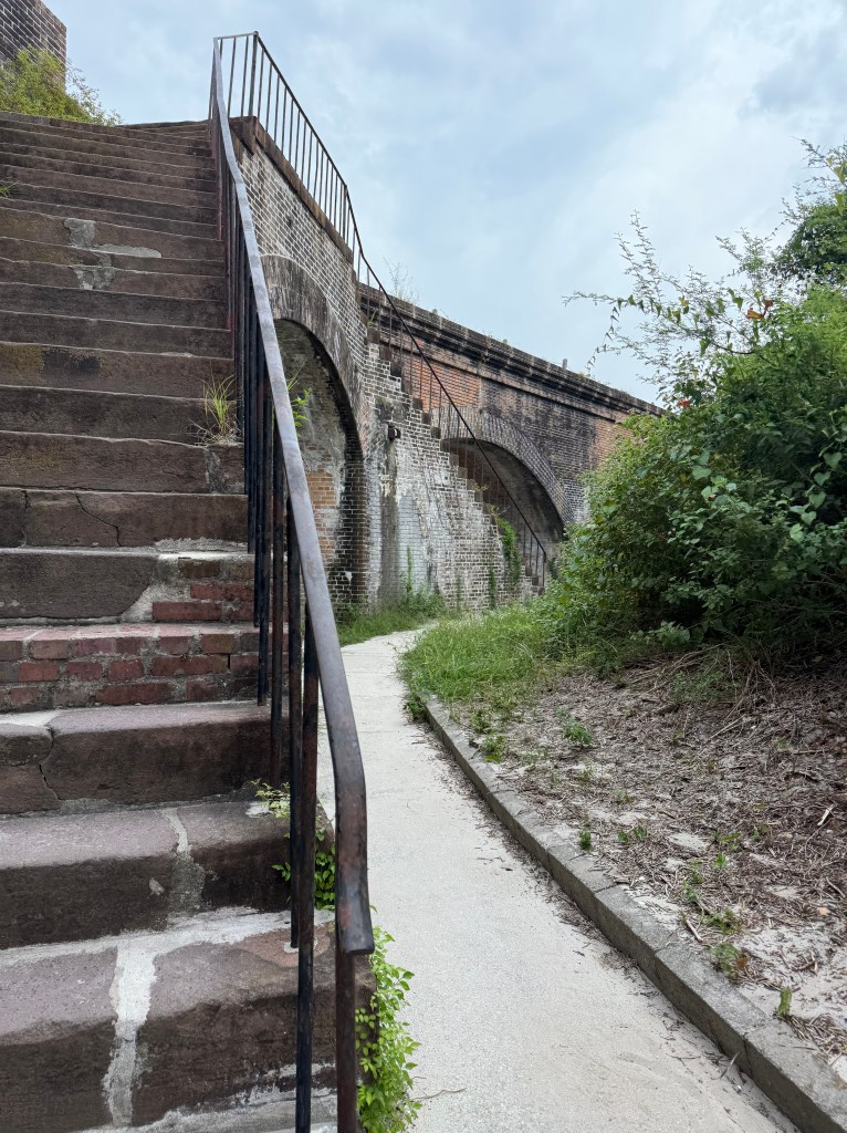 Staircase on the left, sidewalk trail to the right of staircase.