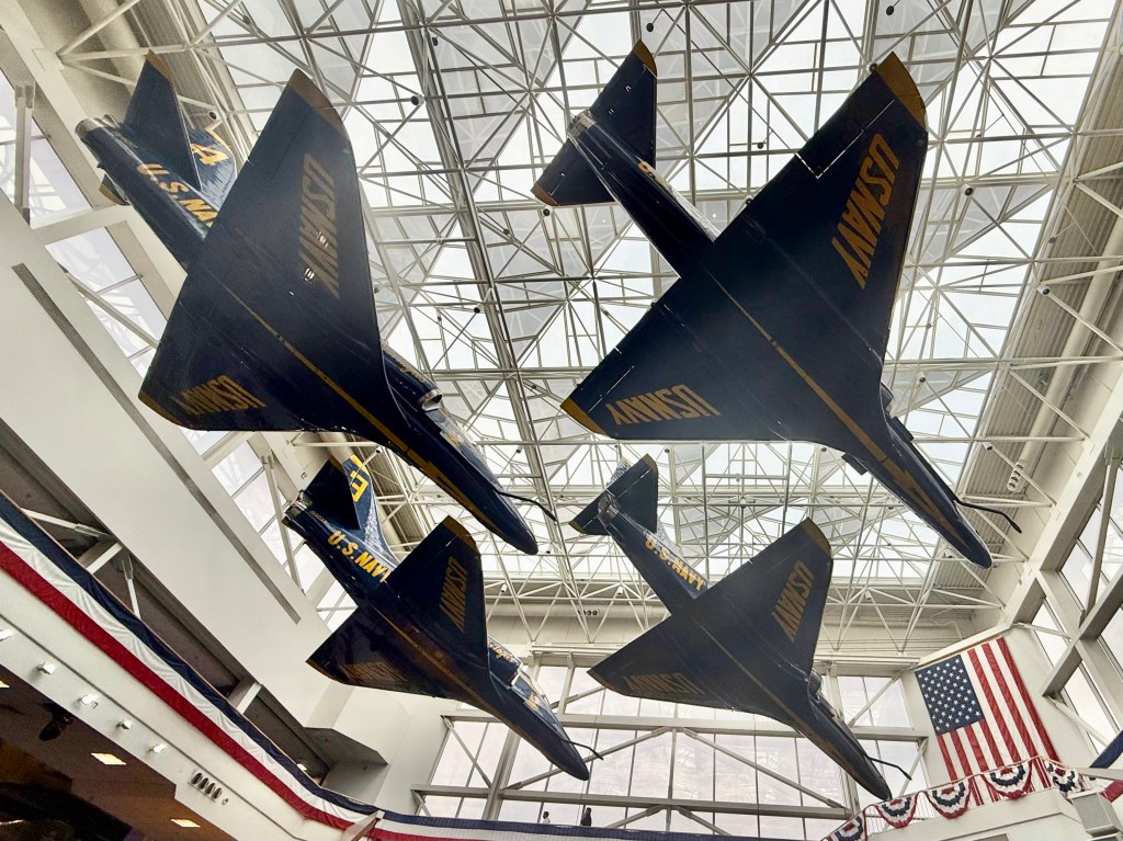 Four Blue Angels aircraft are suspended along the ceiling.